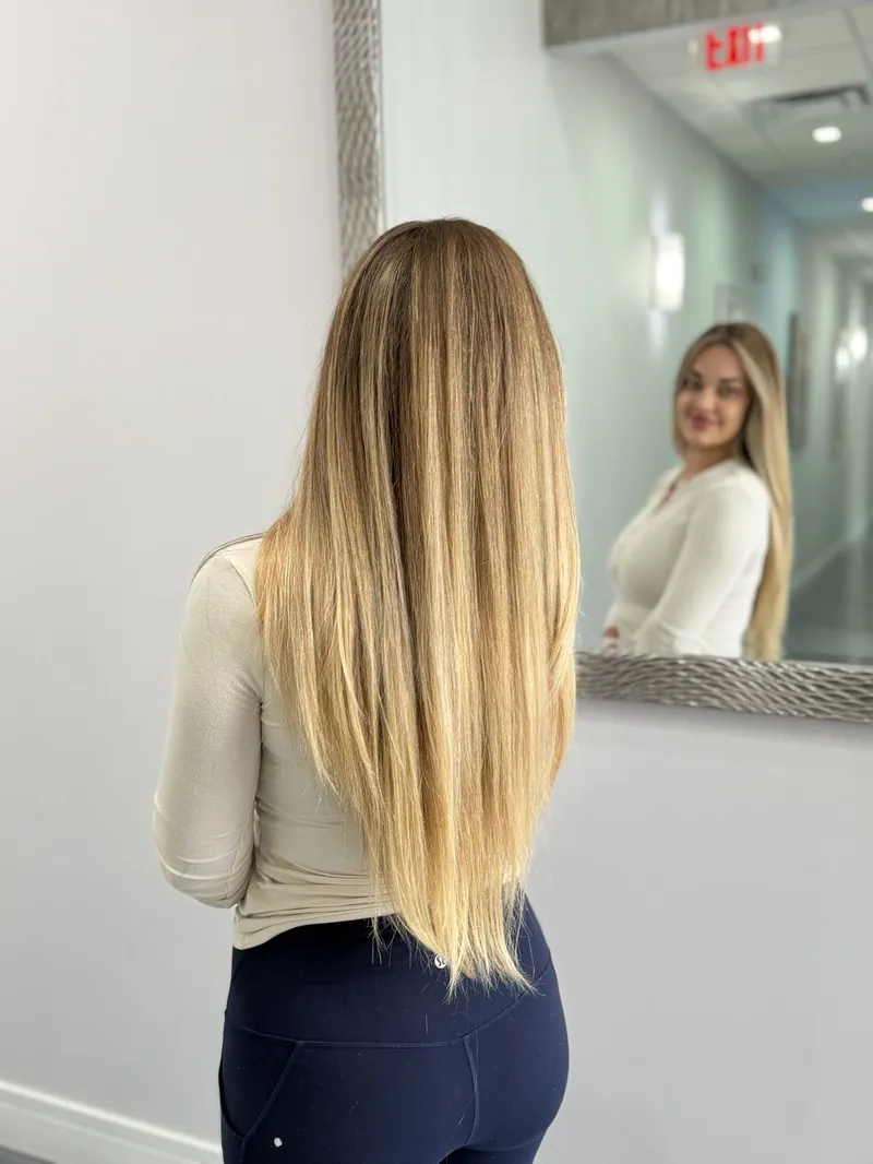 A client admiring her long blonde hair in the suite mirror