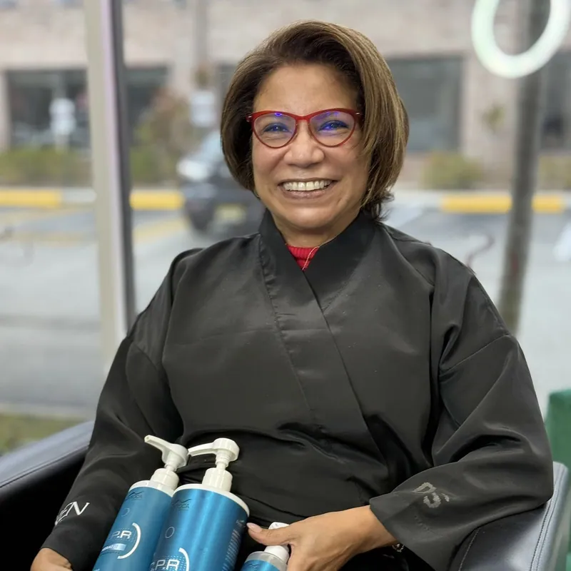 A smiling client in my chair, holding the professional products I use