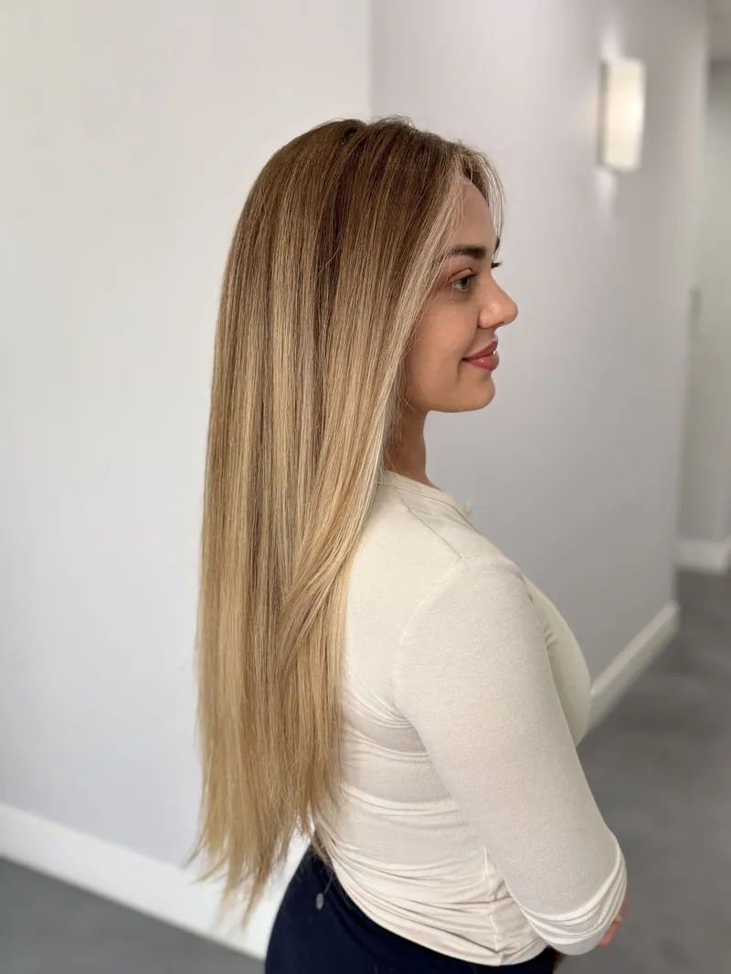 A client in profile with long, seamless blonde balayage